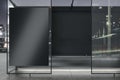 Modern glass bus stop with empty black billboard and reflections on night city background. Mock up Royalty Free Stock Photo