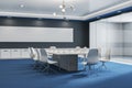 Modern glass meeting or conference room interior with furniture, blue carpet and blank wide black mock up frame on wall. 3D Royalty Free Stock Photo