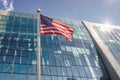 A modern glass skyscraper with an American flag flying in front under a blue sky Royalty Free Stock Photo