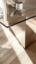 Modern glass table corner on wood floor in sunlit room, interior design Royalty Free Stock Photo