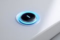 Modern glowing blue illuminated power button on sleek white electronic device symbolizing technology and innovation in a Royalty Free Stock Photo