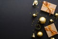 Modern golden Christmas decorations, baubles, gift boxes, confetti stars on dark black background. Flat lay design, top view, copy Royalty Free Stock Photo