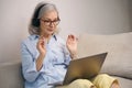 Modern grandmother in glasses and a computer headset