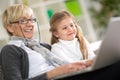 Modern grandmother teaching grandchild how to use laptop