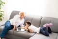 modern grandmother teaching grandchild how to use laptop computer at home