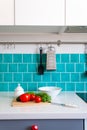 Kitchen features dark gray flat front cabinets paired with white quartz countertops and a glossy blue care tile. Royalty Free Stock Photo