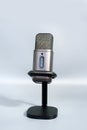 Modern gray microphone on stand against light background Royalty Free Stock Photo