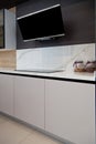 Modern gray white lacquer wood kitchen cabinet and black electric stove and hood on white granite countertop Royalty Free Stock Photo