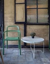 Modern green chair and white round table with green plant in vase decoration in old wooden house background Royalty Free Stock Photo