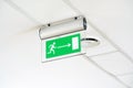 Modern green emergency exit route door arrow sign on the ceiling, object detail, closeup, nobody. Corporate business office Royalty Free Stock Photo