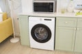 Modern green kitchen interior with washing machine and microwave. Royalty Free Stock Photo