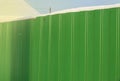 Modern green metal corrugated siding fence, outdoor winter space, safety and security, veneer texture Royalty Free Stock Photo