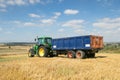 Modern green tractor pulling a trailer in harvest field Royalty Free Stock Photo