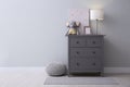 Modern grey chest of drawers near wall in child room, space for text. Interior design