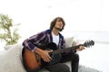 Modern guy playing guitar sitting on the couch. concept of a lifestyle Royalty Free Stock Photo