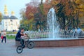 Modern guy riding bicycle in city park with fountains