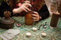 Modern gypsy witch makes love potion. Psychic holds brown pot of drink in which adds magical herbs and mixes it with a wooden Royalty Free Stock Photo