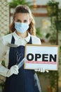 Modern hair salon worker in apron showing welcome sign