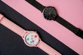 modern hand watches on black pink background, top view