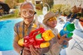 Modern grandmother grandfather and have fun playing with water gun