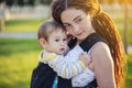 Modern happy mother with baby son in ergo backpack walking in Sunny summer day. Concept of the joy of motherhood Royalty Free Stock Photo