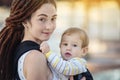 Modern happy mother with baby son in ergo backpack walking in Sunny summer day. Concept of the joy of motherhood Royalty Free Stock Photo