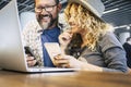 Modern happy youth couple working together with smartphone and laptop. Portrait of cheerful man and woman using computer and Royalty Free Stock Photo