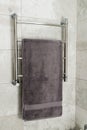 Modern heated towel rail with a gray towel in a gray tiled bathroom