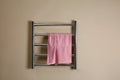 Modern heated towel rail with warm soft towel on beige wall