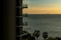 A modern high building with balconies against a sunset sky and beautiful sea with the orange light of sunset, space for copy and Royalty Free Stock Photo