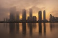 Modern high rise buildings at waterfront covered with fog and haze at sunrise / sunset hour. Royalty Free Stock Photo