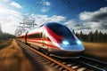 A modern high-speed train moves along the railway tracks against the backdrop of a field at sunset. High-speed rail transport Royalty Free Stock Photo
