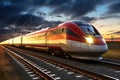 A modern high-speed train moves along the railway tracks in the evening against the backdrop of sunset. High-speed passenger rail Royalty Free Stock Photo