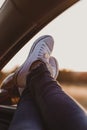 Modern hipster girl resting in a car and admiring view. Woman driver watching sunset put feet on car door. Feet outside the window Royalty Free Stock Photo