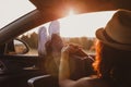 Modern hipster girl resting in a car and admiring view. Woman driver watching sunset put feet on car door. Feet outside the window Royalty Free Stock Photo