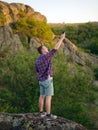 Young man with no internet on a natural background. Traveler climbing rocks for better connection concept. Copy space. Royalty Free Stock Photo