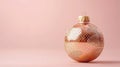 Modern holiday bauble with a shimmering gold snake skin texture, contrasted against a minimalist blush pink background