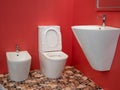 Modern home bathroom interior design with white washbasin, toilet, bidet and vivid red walls Royalty Free Stock Photo