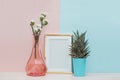 Modern home decor mock up with gold blank photo frame, vase and tropical plant on pink blue background Royalty Free Stock Photo