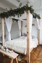 Modern home interior design. Cozy bed with wooden canopy and pillows, blanket. Bedroom interior, scandinavian style.