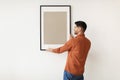 Young man hanging picture frame on the wall Royalty Free Stock Photo