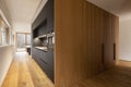 Modern home interior with white walls and a parquet on the floor. Modern black kitchen and large cupboards