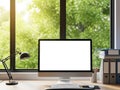 Modern home office setup with computer screen facing lush green trees through large window Royalty Free Stock Photo