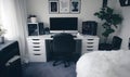 modern minimalist home office setup with white desk black chair computer speakers and indoor plants in cozy room Royalty Free Stock Photo