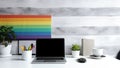 A modern home office setup with laptop on desk and a rainbow poster on wall, for pride day. Generative AI Royalty Free Stock Photo