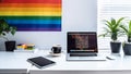 A modern home office setup with laptop on desk and a rainbow poster on wall, for pride day. Generative AI Royalty Free Stock Photo