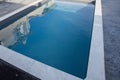 Modern home swimming pool with stone coping with grey waxed concrete terrace and blue transparent water