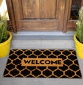 Modern honeycomb patterned yellow black welcome zute doormat outside home with yellow flowers and leaves Royalty Free Stock Photo