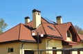 Modern house attic roof with skylight windows, roof gutter, chimneys and solar panels. Royalty Free Stock Photo