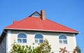 Modern house with attic window,  red metal roof and white plastic rain gutter. Roofing construction Royalty Free Stock Photo